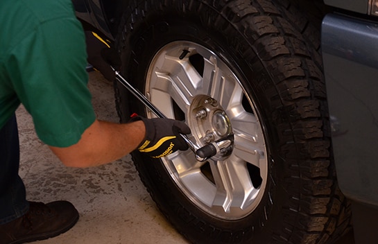 Mechanic using a breaker bar to loosen the truck’s lug nuts